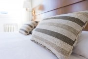 Closeup of striped pillows on white bed.